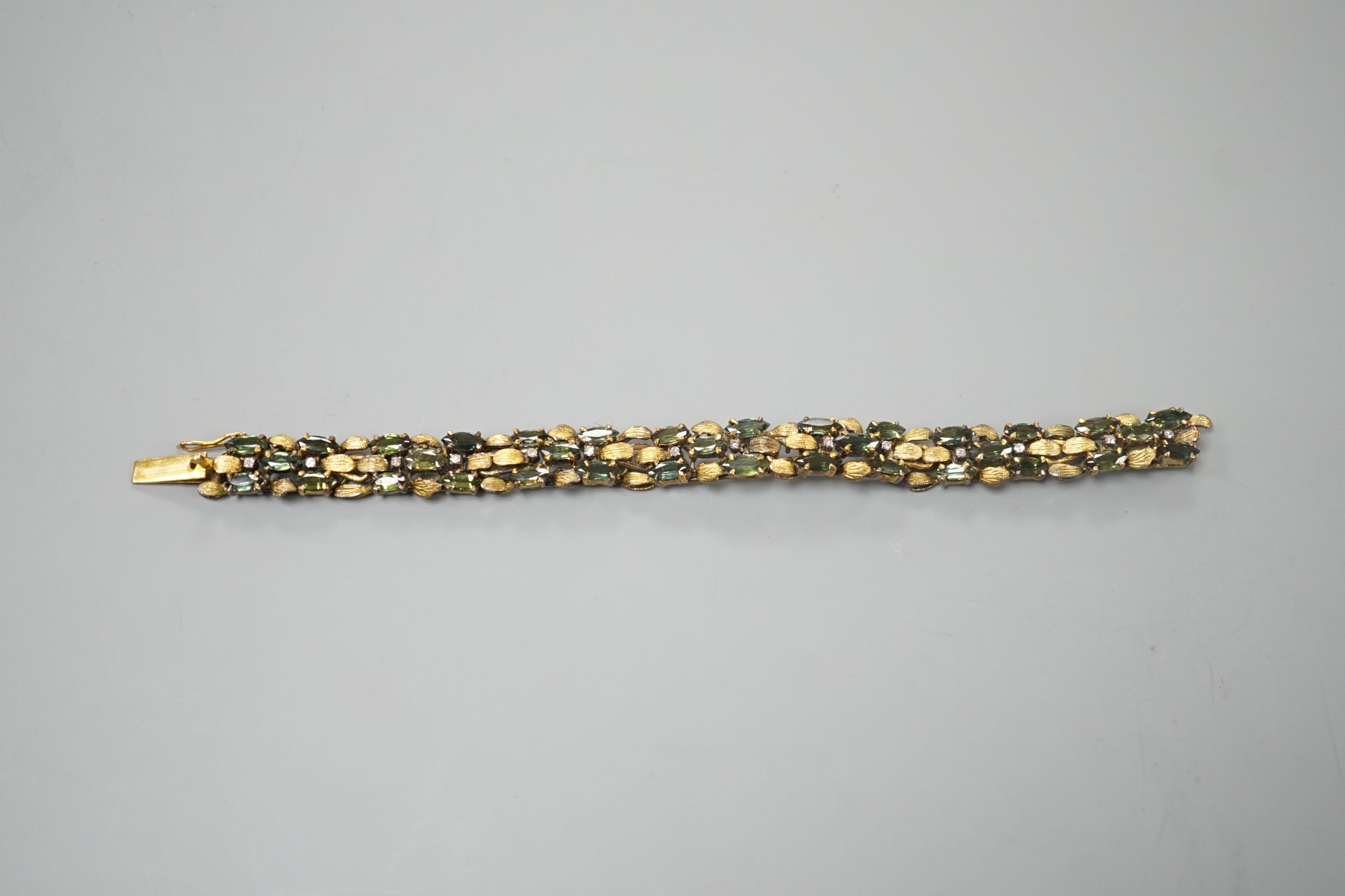 A modern yellow metal, multi green stone and multi diamond chip set bracelet, 16.5cm, gross weight 23.8 grams.